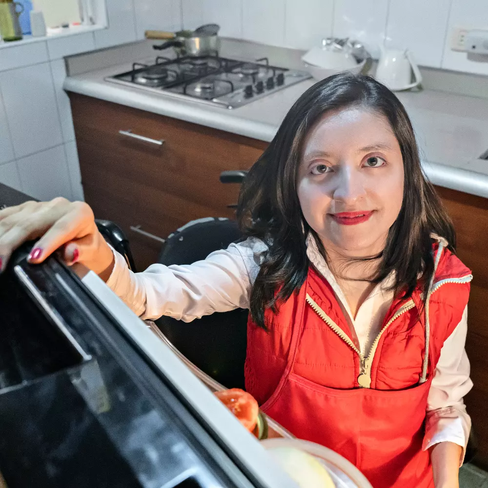 Disabled woman in kitchen opening fridge door