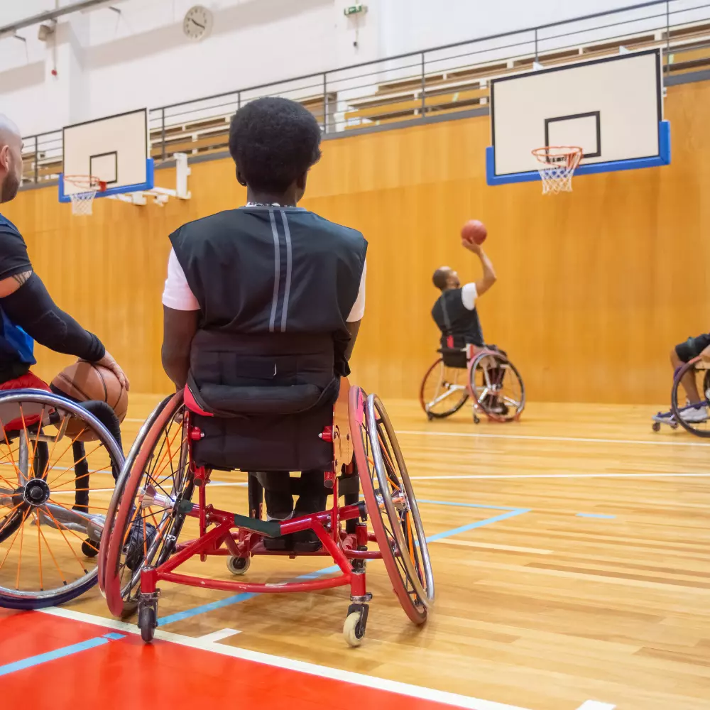 Group of men in wheelchairs playing basketball in centre based environment