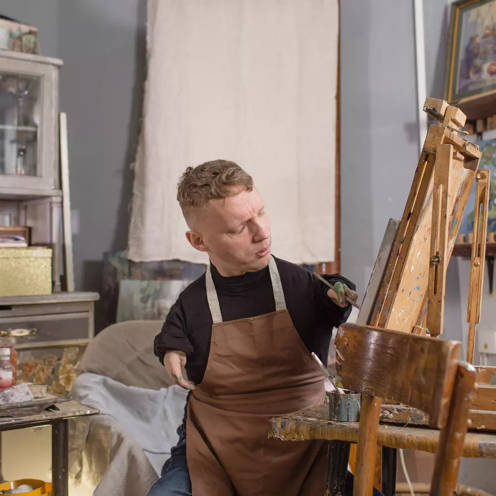Man with physical disability painting in art class