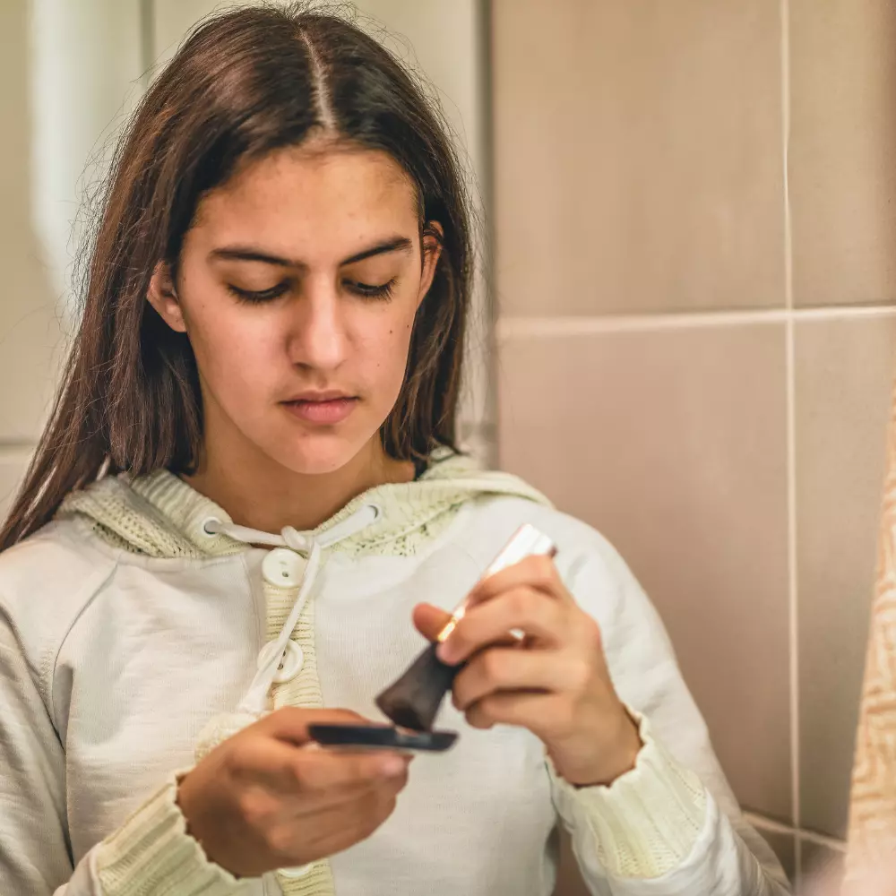 Woman putting on make up in mirror
