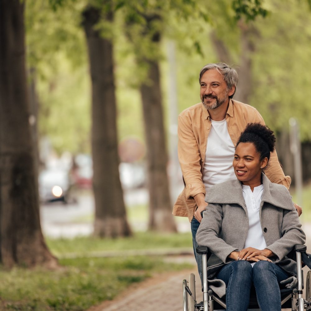 Man taking care of her disabled woman, walk.